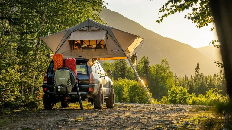Vehículo equipado para acampar entre árboles y montañas